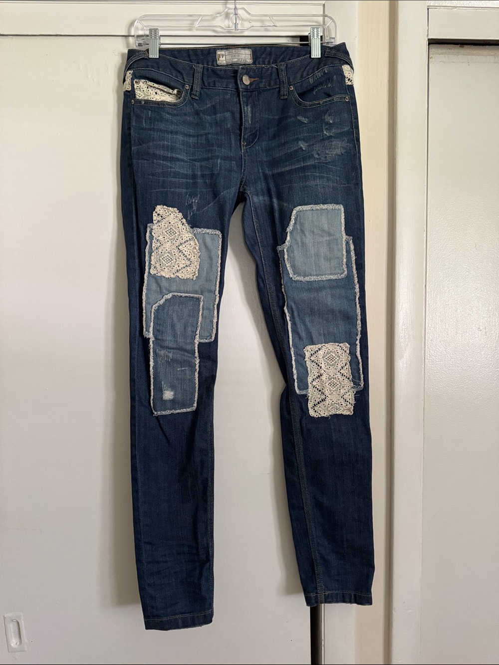 Free People skinny jeans with crochet lace and patching details. 32” inseam.